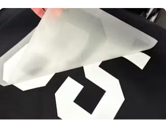 Carrier film peeling from a white number transfer on black fabric