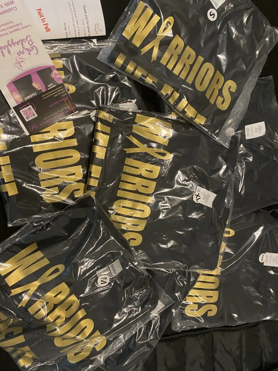 Packaged black Warriors shirts with repeated gold lettering for a coordinated printed apparel run