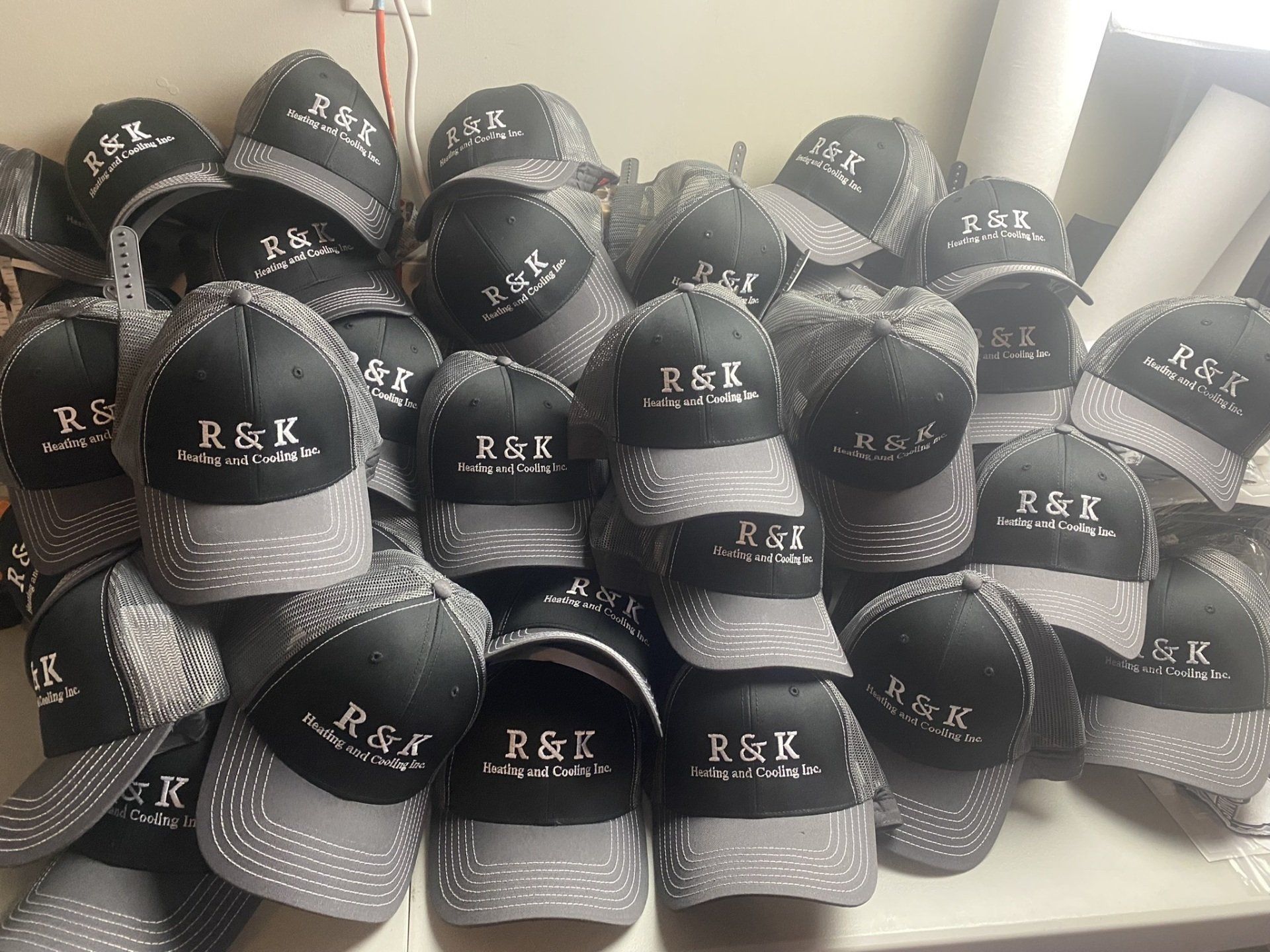Black and gray caps with stitched R&K logos, illustrating embroidery on headwear